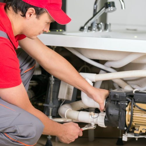 Plumber repairing pipes under kitchen sink
